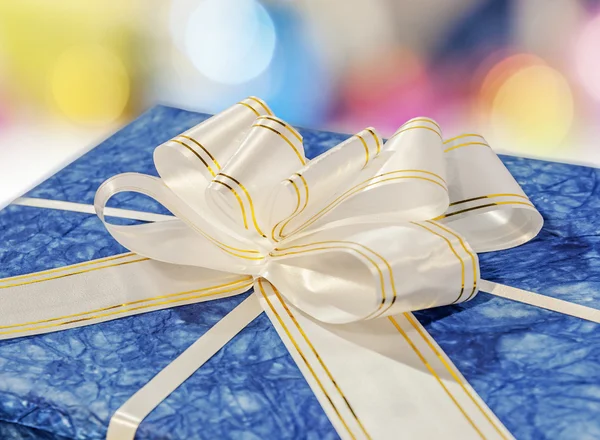 Blue gift box with white and golden ribbon and bow