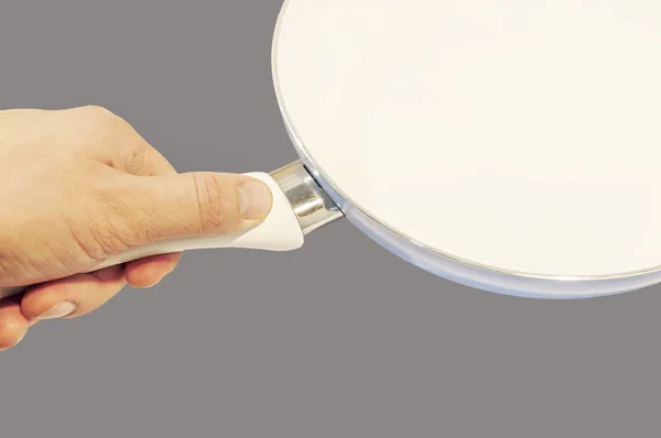 Hand holding frying pan isolated on grey background