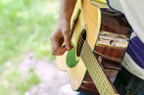 Young guitar player playing song outdoor in park