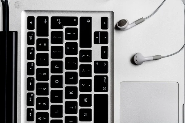 Top view of the keyboard of the laptop on white Desk with headphones