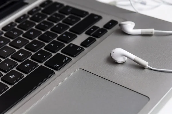 Top view of the keyboard of the laptop on white Desk with headphones