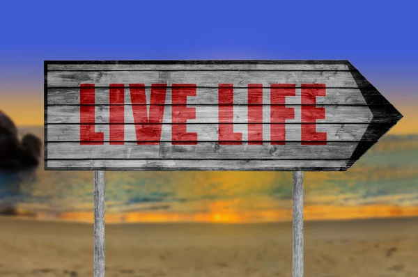 Red Live Life wooden sign with a beach on background