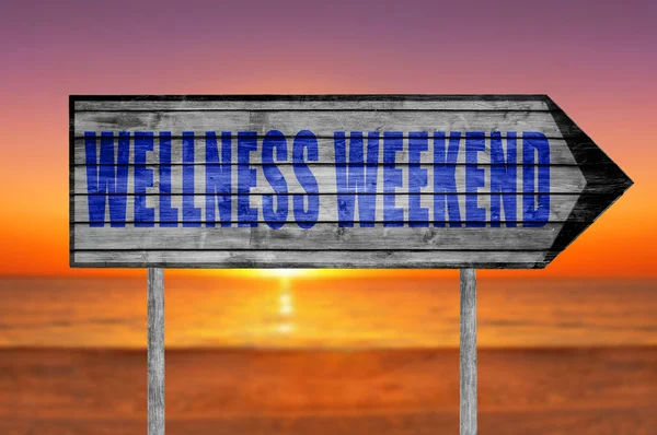 Wellness Weekend wooden sign with on a beach background