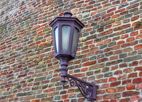 Glowing lantern on vintage brick street wall