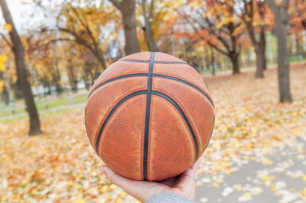Basketball in hand close in yellow park background