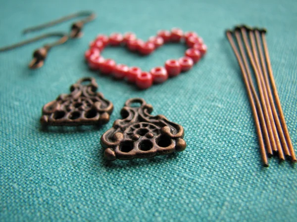 Red beads in form of heart, making of earrings, handmade jewelry