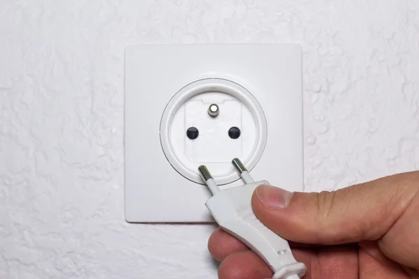 Hand plugs cord in socket