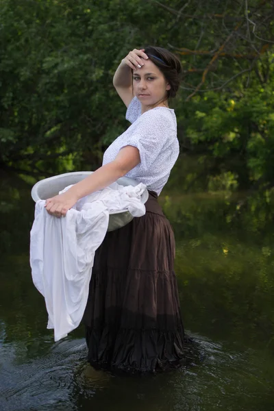 Peasant woman washes clothes in the river