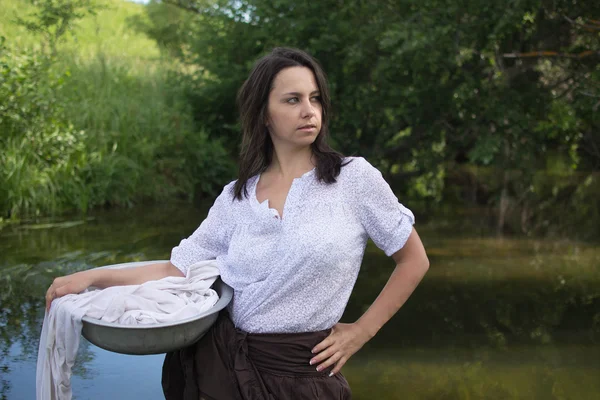 Peasant woman washes clothes in the river