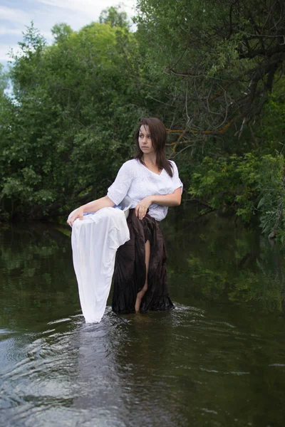 Peasant woman washes clothes in the river