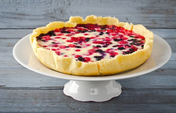 Mix berry tart, pie, cake with raspberries, bilberries, bluberries, red currant and cream, copy space