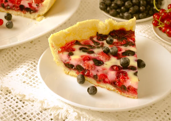 Mix berry tart, pie, cake with raspberries, bilberries, bluberries, red currant and cream on white background