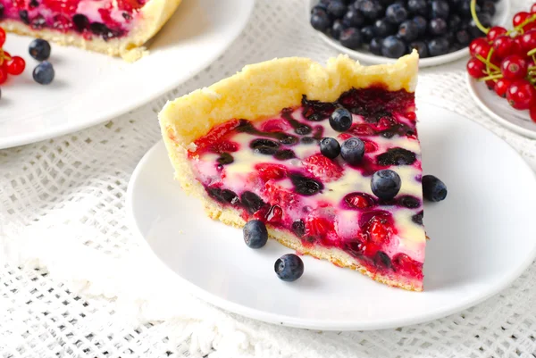 Mix berry tart, pie, cake with raspberries, bilberries, bluberries, red currant and cream on white background
