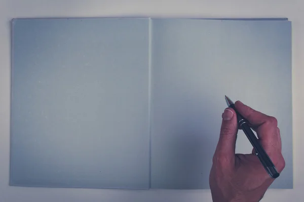Holding pencil over blank page of a empty book