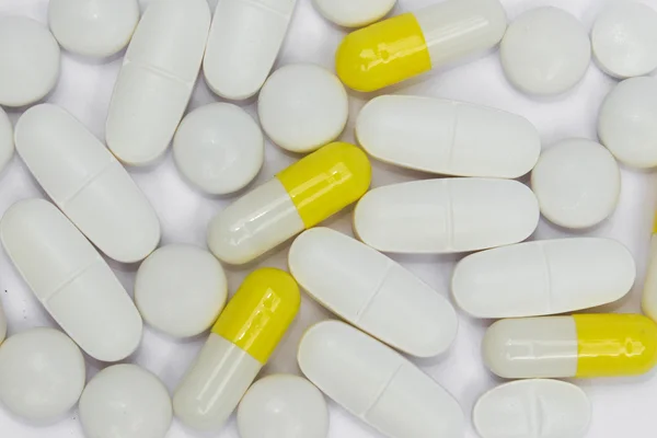 White pills macro yellow capsules close up