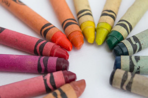 Old wax crayons on white paper - vintage color pencils closeup