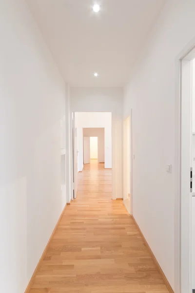 Fresh renovated flat corridor, white walls, wooden floor