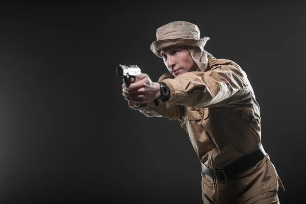 Soldier with a gun takes aim on dark background