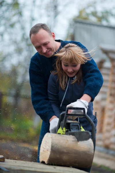 Couple in autumn home garden sawing wood