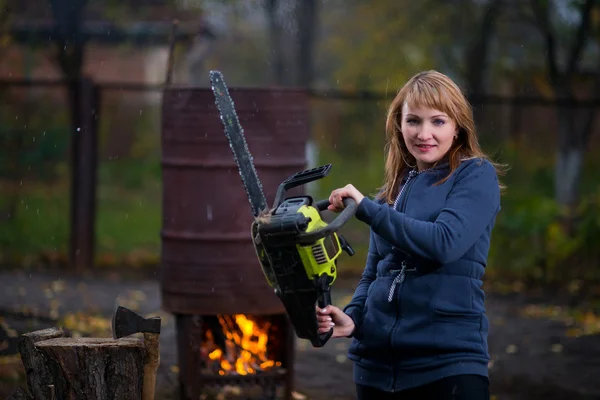 Woman in autumn home garden sawing wood
