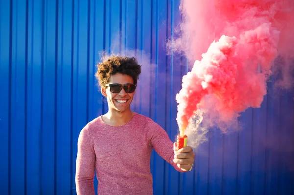 Man smiling and holding pink smoke