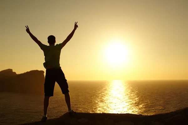 Silhouette of a man with raised arms on sunset
