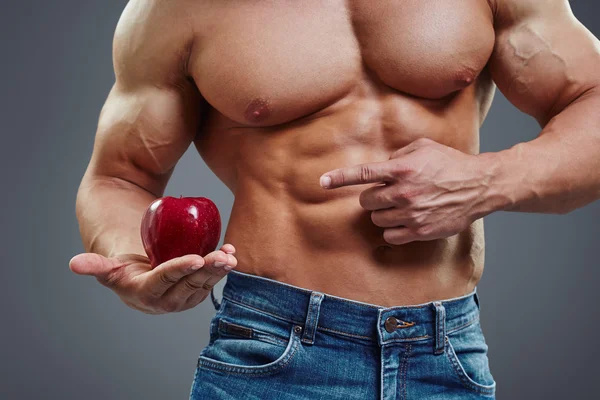 Fit man pointing to fresh red apple.