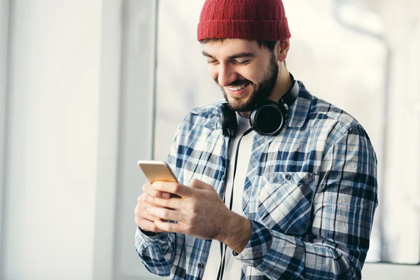 Hipster man using smart phone at window.