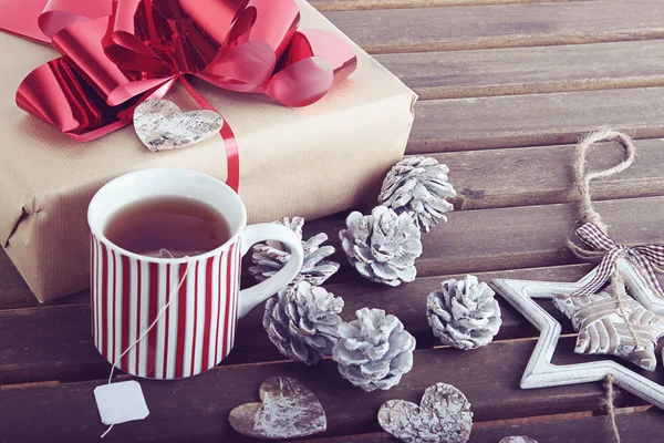 Christmas present, decoration and warm tea on wooden background
