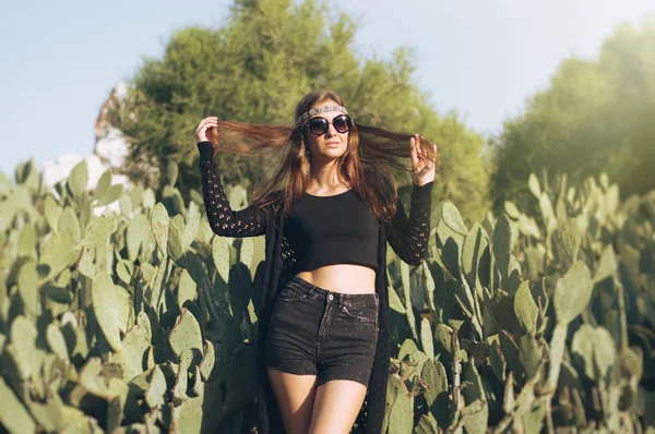 Young hippie woman with long hair standing near cactus, retro