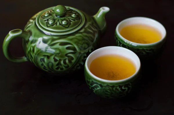 Green tea in two small cups and chinese traditional tea kettle