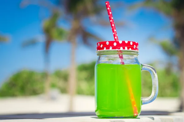 Juice of bright green color in a glass with a red straw