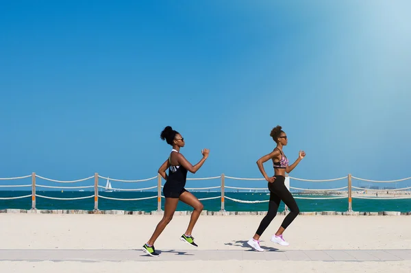 Two african females jogging along Dubai beach in United Arab Emi