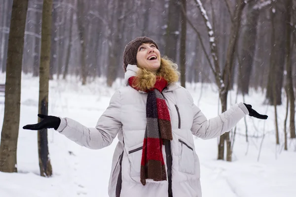 Young beautiful girl close up in winter park enjoys snow fell