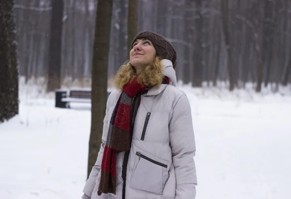 Young beautiful girl close up in winter park enjoys snow fell