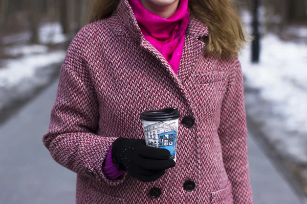 Beautiful young woman walk outdoor in park with plastick cup of coffee, that she takes in your hands