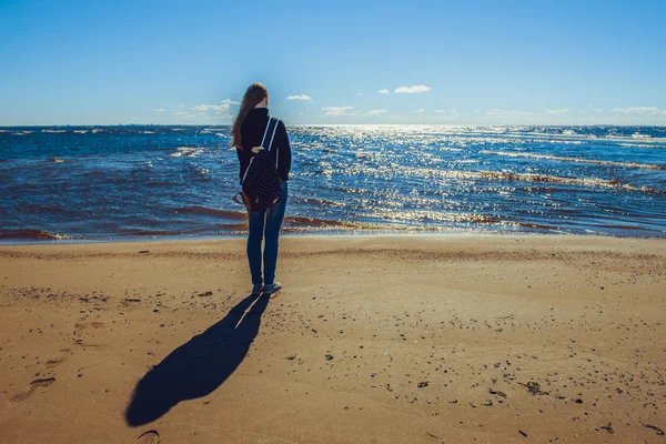 Young woman at the seaside sees off last summer day.