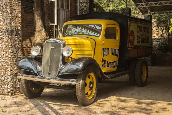 Yellow old model Chevrolet pickup truck in the patio of ancient cafe Tan Malie Se Winkel 1921. Vintage car style.
