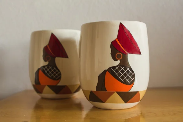 Coffee mugs. Traditional african handmade  style. Craftsmanship. Image beautiful african woman in ethnic clothes, hat. Souvenirs.