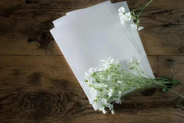 Composition with a sheet of paper and white small flowers on a w