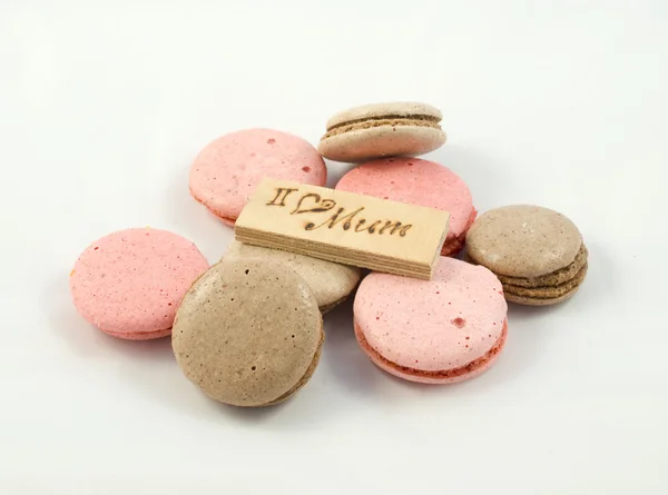 Chokolate and pink macarons chaotically arranged and a board with the inscription I love mum. A Happy Mother\'s Day theme