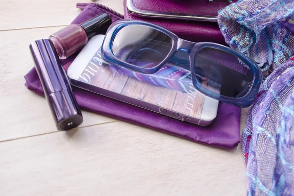 Fashionable female accessories watch sunglasses lipstick violet clutch and mobile phone. Woman's things.