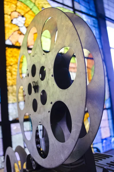 Reel of cinema projector. Old and antique part of commercial movie projector on a background of stained glass.