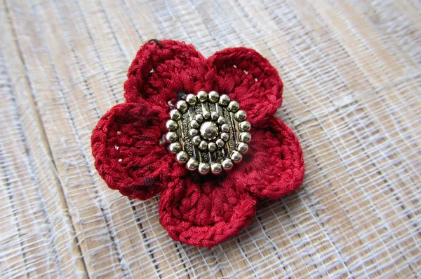 Single knitted poppy flower head on tissue background. Handmade.