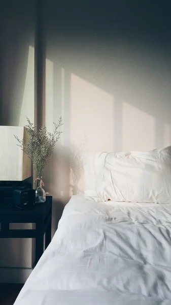 Warm morning light and shadow over a fluffy relax white bed