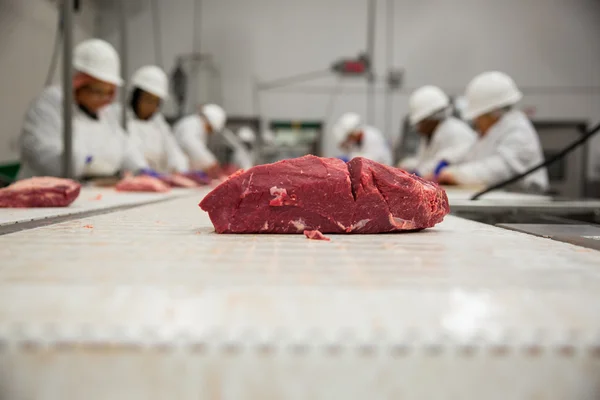 Meat handling safety procedure with workers in white suits helmets and gloves