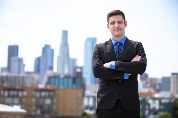 Young business man attorney arms folded proudly standing in the city building background