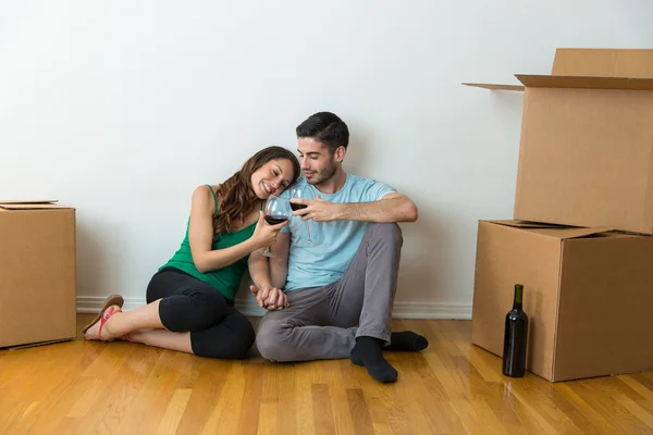 Couple lovers moving into new home cardboard boxes enjoying wine