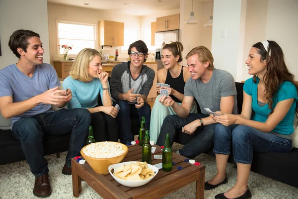 A group of friends college students young adults together playing poker cards