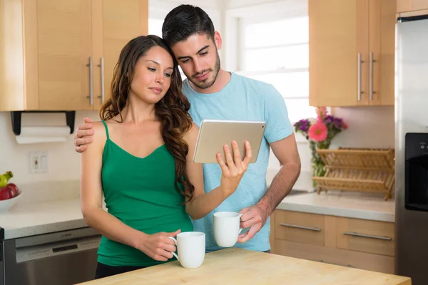 Endearing couple looking at videos online on a smart tablet sad emotional love sweet hug